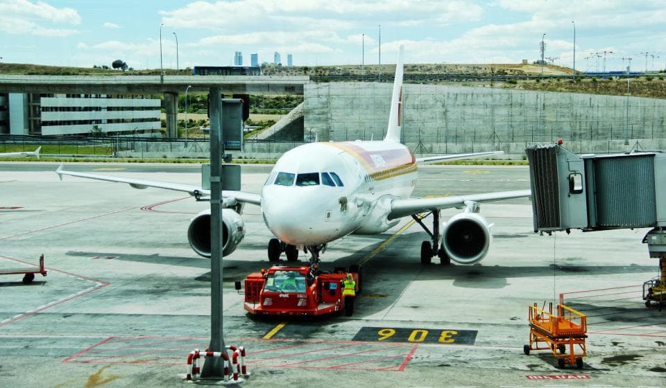An airliner parked at the gate with ground crew alongside.