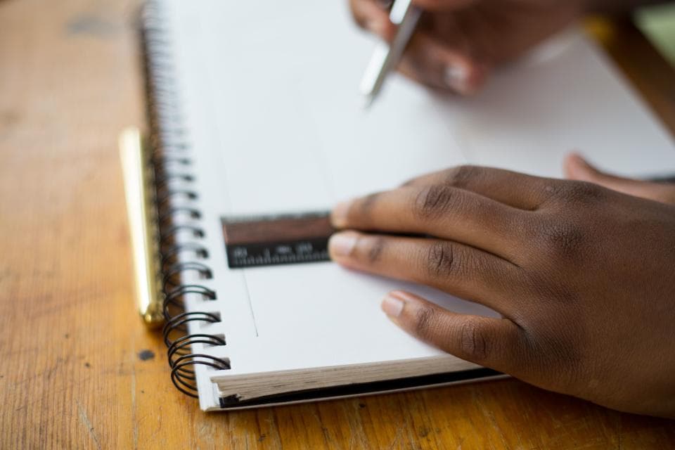 A hand writing notes in a ruled notebook.