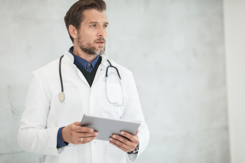 A doctor with a stethoscope holding a tablet.