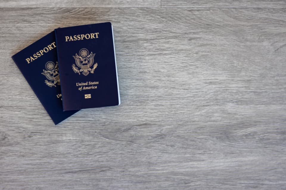 Two passports on a wooden desk.